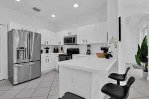 a kitchen with white cabinets and a stainless steel refrigerator at Miami home -15min from Kendall Exec Airport - Pool in Hammocks
