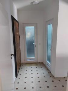 a white room with two doors and a tiled floor at River Side Apartment in Prizren