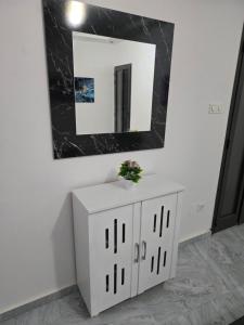 a bathroom with a mirror and a white cabinet at SUITE RESIDENCE TERANGAWALo in Richard Toll