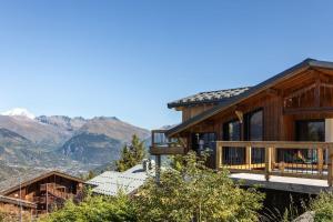 ein Haus auf einem Hügel mit Bergen im Hintergrund in der Unterkunft Chalet Mathilde Les Coches Saturday Changeover in Les Coches
