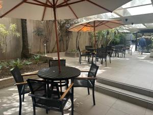 a table and chairs with umbrellas on a patio at Flat poeta Drumond in Sao Paulo