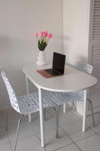 a white table with a laptop and pink flowers on it at Grand Studio avec piscine in Cul de Sac