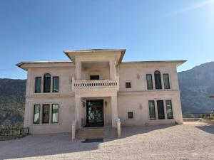 a large pink house with a front door and mountains at Karadut Otel Nemrut in Karadut