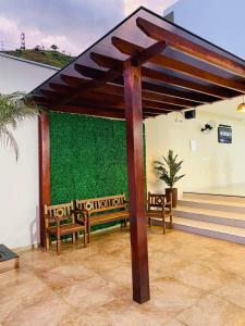 a patio with two benches and a green wall at Espaço Beatriz in Aparecida