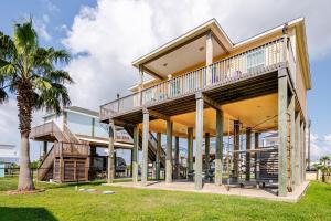 a house with a deck and a palm tree at Welcome To Sarenity a 3Bd 2Bth home in Crystal Beach, Tx in Bolivar Peninsula