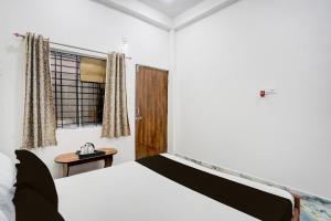 a bedroom with a bed and a window and a table at Hotel O MN Palace in Jabalpur