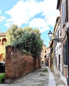 an alley with a brick wall and a street at Paloma13 in Ferrara