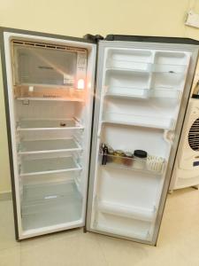 an empty refrigerator with its door open in a kitchen at Shreya's Homestay, Your Sacred Nest in Ujjain