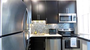 une cuisine avec des armoires noires et un réfrigérateur en acier inoxydable dans l'établissement The Belvedere Unit 2C, à Cape May