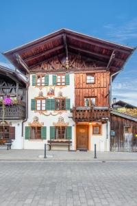 un edificio con tenda da sole e panca davanti di Stube & Stories - Heritage Riverside Home a Garmisch-Partenkirchen
