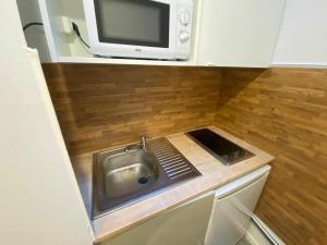 Una pequeña cocina con fregadero y microondas. en Zola Saint Ouen, en Saint-Ouen