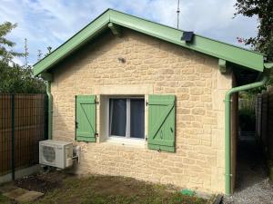 een klein bakstenen huis met groene luiken en een raam bij La landaise in Dax