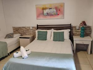 a bedroom with two beds and a nightstand and a bed sidx sidx sidx sidx at Pousada Bela Casa Geribá in Búzios