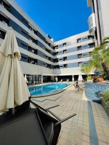 サルバドールにあるUNU The Plaza Ondinaのプールと傘付きの椅子があるホテル