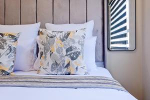 a bed with white sheets and pillows and a window at Prime Ridge in Midrand +17 photos