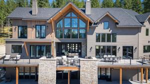 a large house with a deck with tables and chairs at Great Northern Mountain Escape in Whitefish