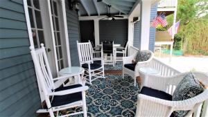 - une terrasse couverte avec des chaises à bascule blanches et une table dans l'établissement Heritage House 2, à Cape May