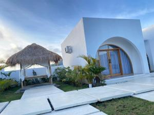 a white house with a straw umbrella and a table at The Dream Hill Bali - Kintamani in Kubupenlokan