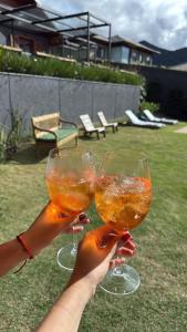 two people holding up wine glasses in a yard at Casa 02 Monte Boa Vista - Casa de 4 Suítes com Vista Deslumbrante in Teresópolis