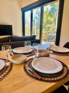a wooden table with plates and wine glasses on it at Henko 1 in Villa La Angostura