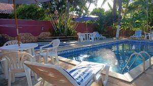 a pool with chairs and tables and an umbrella at Super Flats Geribá in Búzios