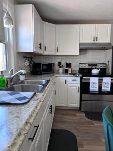 a kitchen with white cabinets and a sink and a stove at Mendon Oasis in Woonsocket