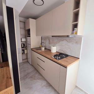 une cuisine avec des armoires blanches et un four à plaques de cuisson dans l'établissement Downtown Studio, à Râmnicu Vâlcea