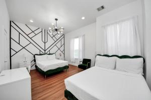a white bedroom with two beds and a chandelier at Stylish Rooftop - East Downtown 3BR Near Everything in Houston