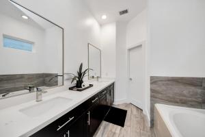 a bathroom with two sinks and a tub and a mirror at Stylish Rooftop - East Downtown 3BR Near Everything in Houston +41 photos