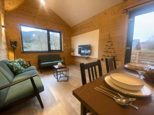 a living room with a table and a dining room at Chalet Iris, spa privatif, 4p in Rochesson