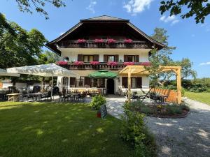 ein großes Haus mit Tischen und Stühlen in einem Hof in der Unterkunft Esterer in Grödig