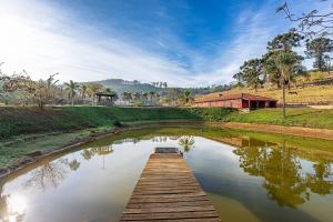 a bridge over a pond with a building in the background at Fazenda com 3 espaços independentes - 10 suítes com PISCINA, 4 suítes com JACUZZI ou Chalé romântico com JACUZZI - Wi-Fi 400MB Lagos e Cavalos in Pedra Bela