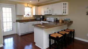 a kitchen with white cabinets and a island with bar stools at Beautiful 4 Bedroom Condo With Pool! in Cape May