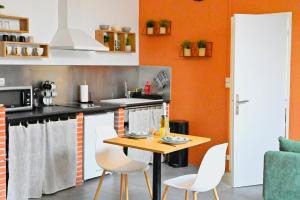 a kitchen with orange walls and a table and chairs at La Dune in Salin-de-Giraud +3 photos