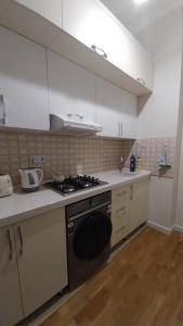 a kitchen with white cabinets and a stove top oven at Banu House in Sumqayyt