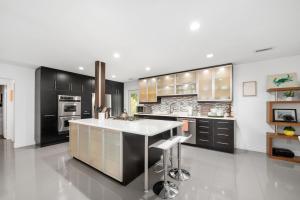 a kitchen with black cabinets and a white counter top at UF SUNSHINE HOUSE - Patio & BBQ - Chef Kitchen - EV Car Station - Upscale Neighborhood! in Gainesville