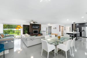 a living room with a glass table and white chairs at UF SUNSHINE HOUSE - Patio & BBQ - Chef Kitchen - EV Car Station - Upscale Neighborhood! in Gainesville