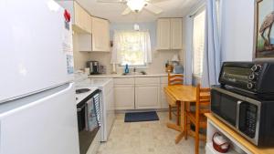 una cucina con mobili bianchi e un tavolo con un forno a microonde di Dottys Cottage a Cape May