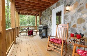 a porch of a cabin with a grill and a rocking chair at Cozy Stone Cabin Retreat Near Beech Ski Slopes in Beech Mountain