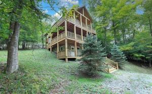a large wooden house in the middle of a forest at Cozy Stone Cabin Retreat Near Beech Ski Slopes in Beech Mountain
