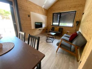 Una sala de estar con una mesa y sillas y un televisor. en Chalet muguet & spa privatif, en Rochesson