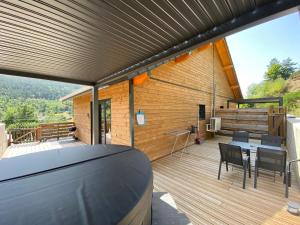 una casa con terraza con mesa y sillas en Chalet muguet & spa privatif, en Rochesson
