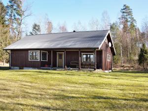 a brown house with a black roof on a grass field at Holiday Home Brunkelstorp in Osby