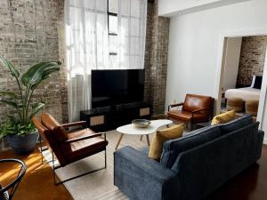 a living room with two couches and a tv at Stylish Industrial Loft in Warehouse District in New Orleans