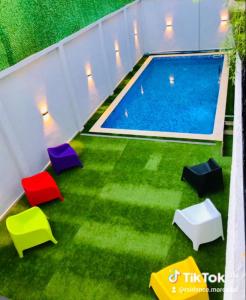 Una piscina con sillas de colores en el césped. en Résidence touristique marcadal by Mon rêve, en Fort de lʼEau