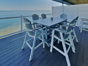 a wooden table and chairs on a deck with the ocean at Put-in-Bay Waterfront Condo #211 in Put-in-Bay
