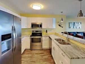 a kitchen with white cabinets and a stainless steel refrigerator at Put-in-Bay Waterfront Condo #211 in Put-in-Bay