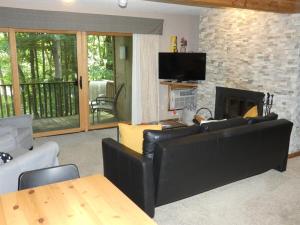 un soggiorno con divano in pelle nera e camino di Timber Ridge Retreat a Bellaire