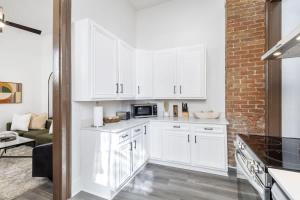 a kitchen with white cabinets and a brick wall at Delightful Canal Street Family Home in Mid-City in New Orleans