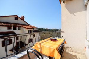 een tafel met een geel tafelkleed op een balkon bij Apartments Biserka in Štanga